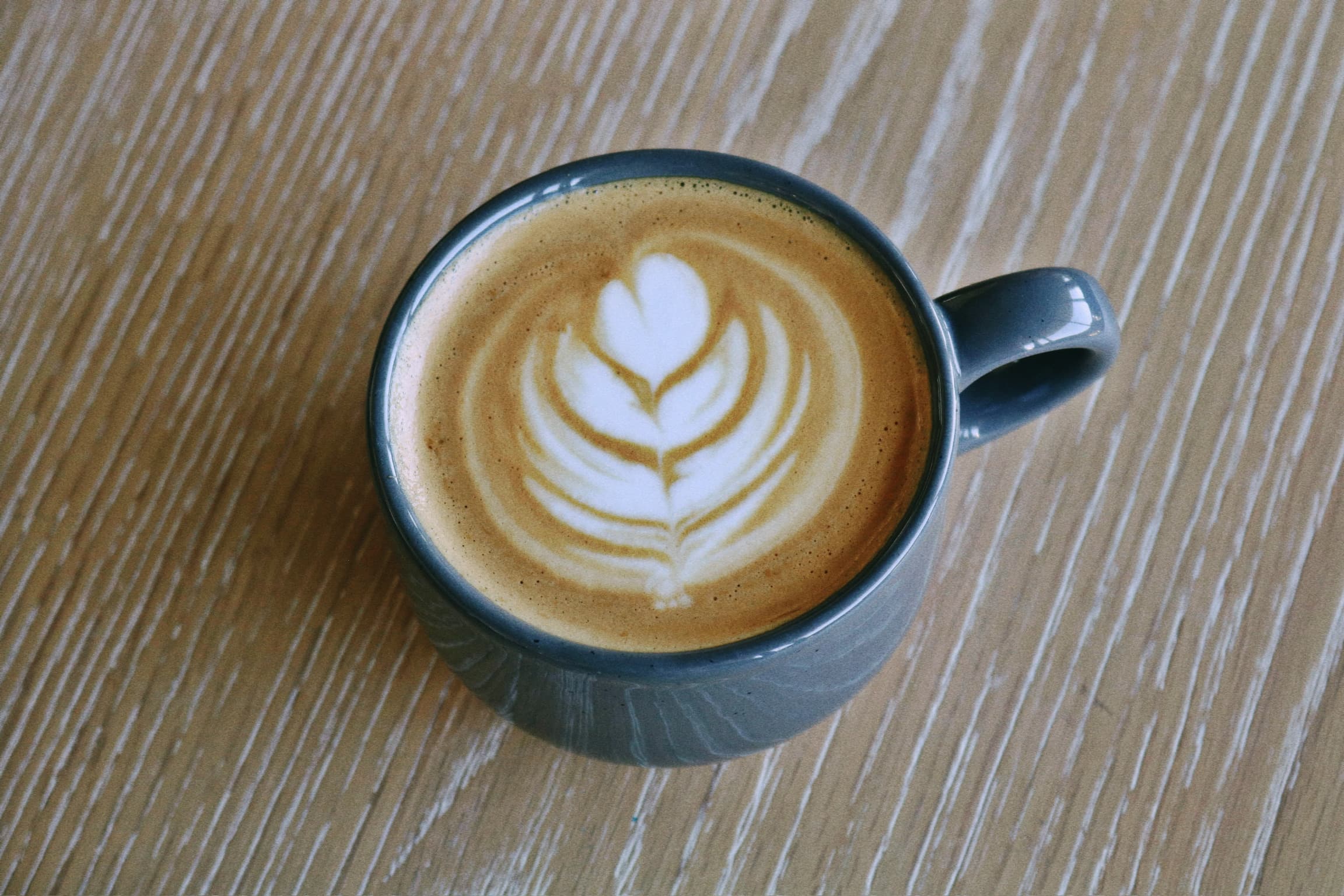 Top-down view of a latte with a tulip pour in a slate-colored mug